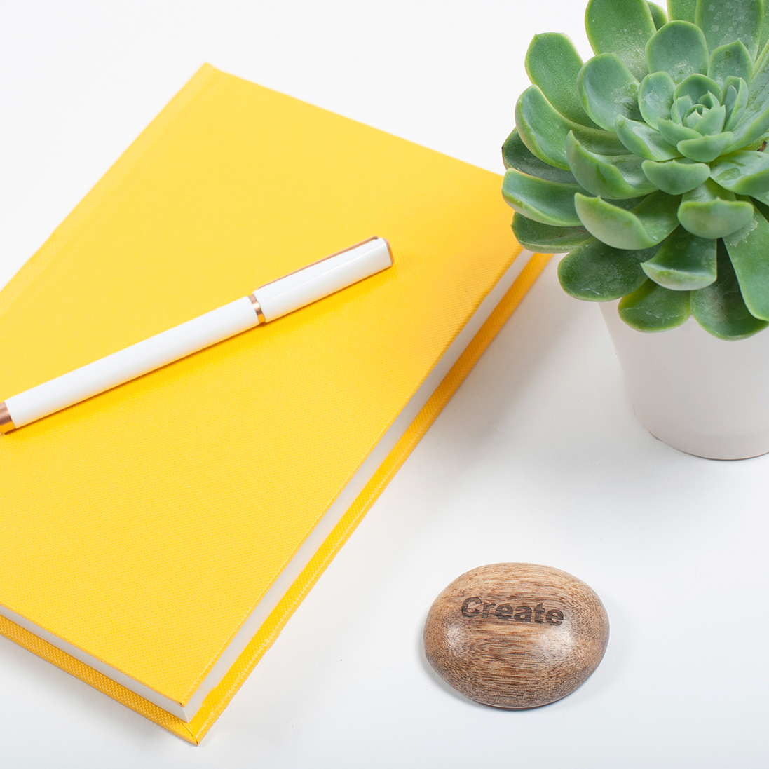 Yellow notebook, pen and plant