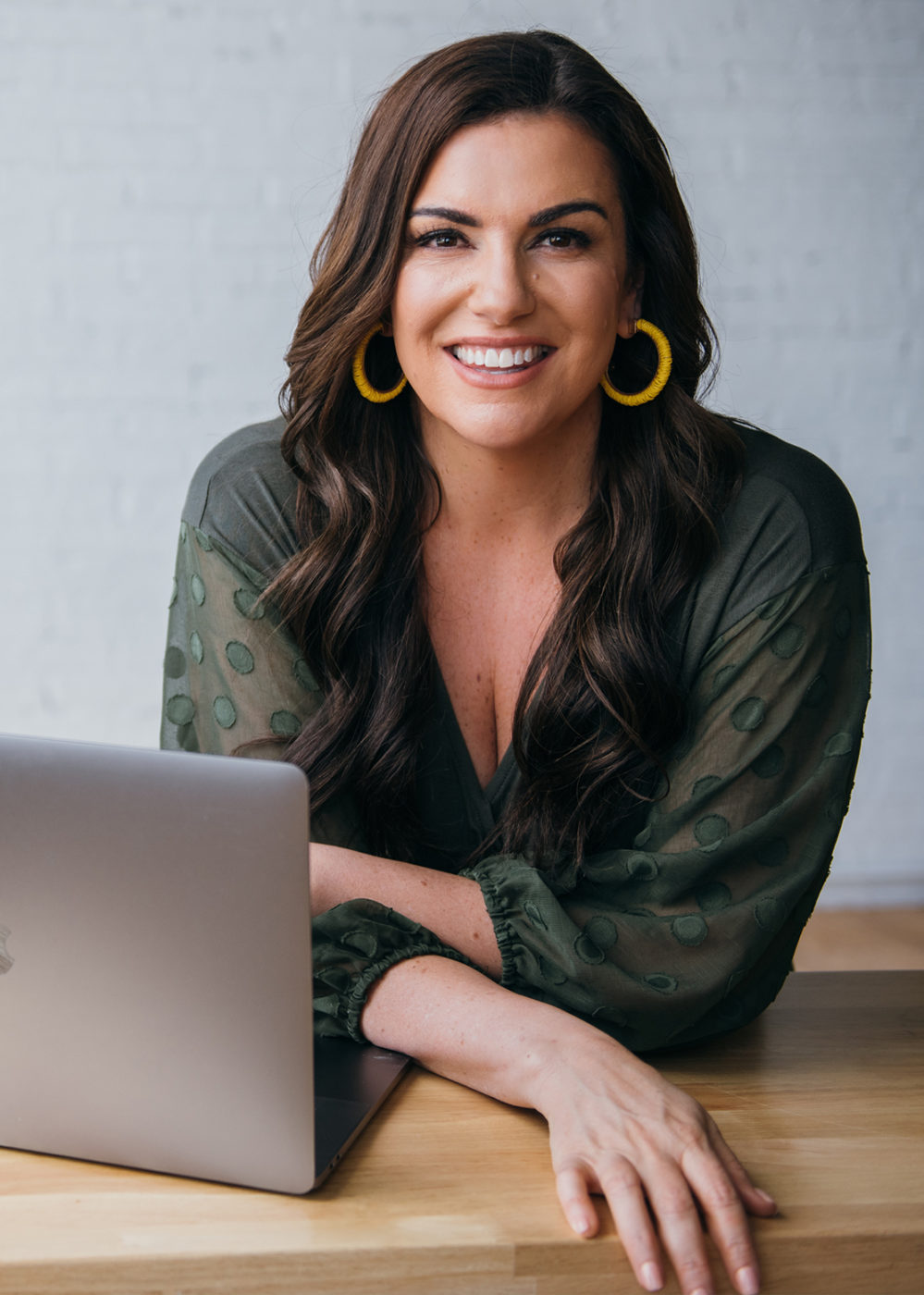Amy Porterfield wearing yellow earrings with macbook