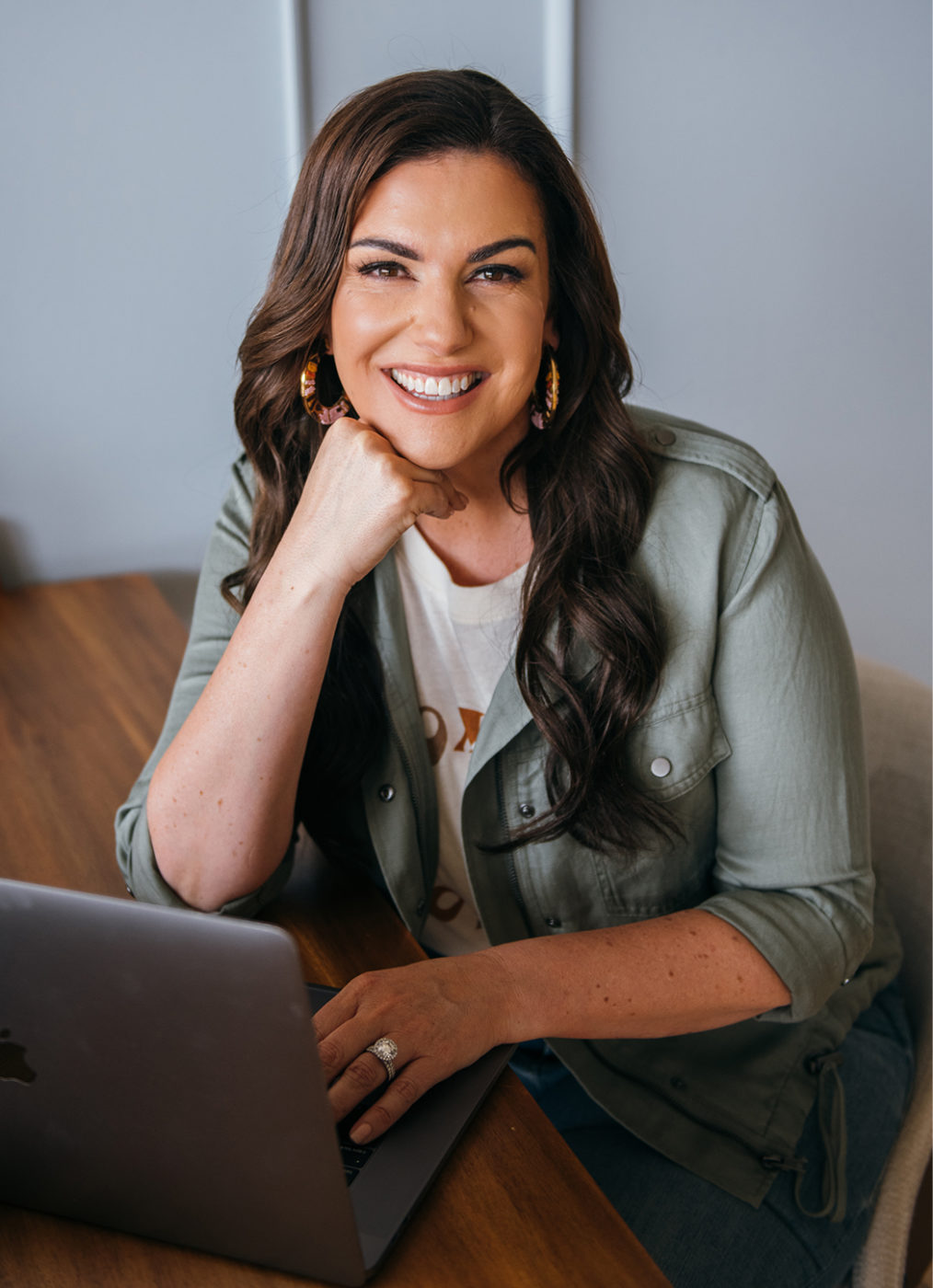 Amy Porterfield smiling with macbook and green jacket