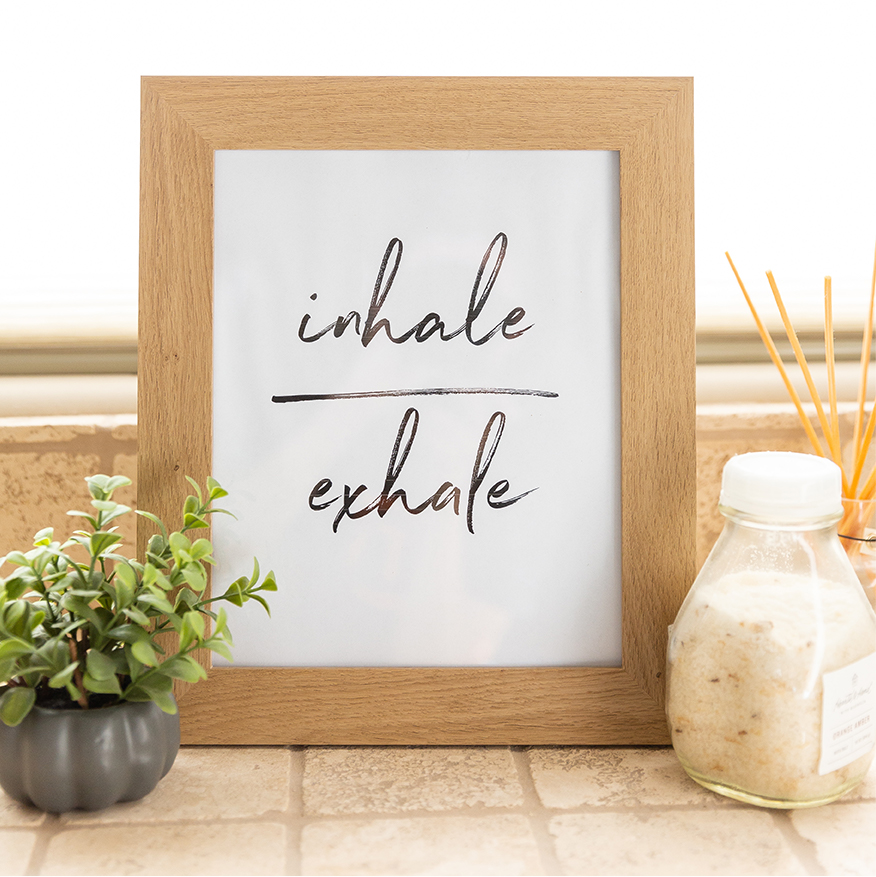 Whiteboard that reads "Inhale Exhale" with plant beside it