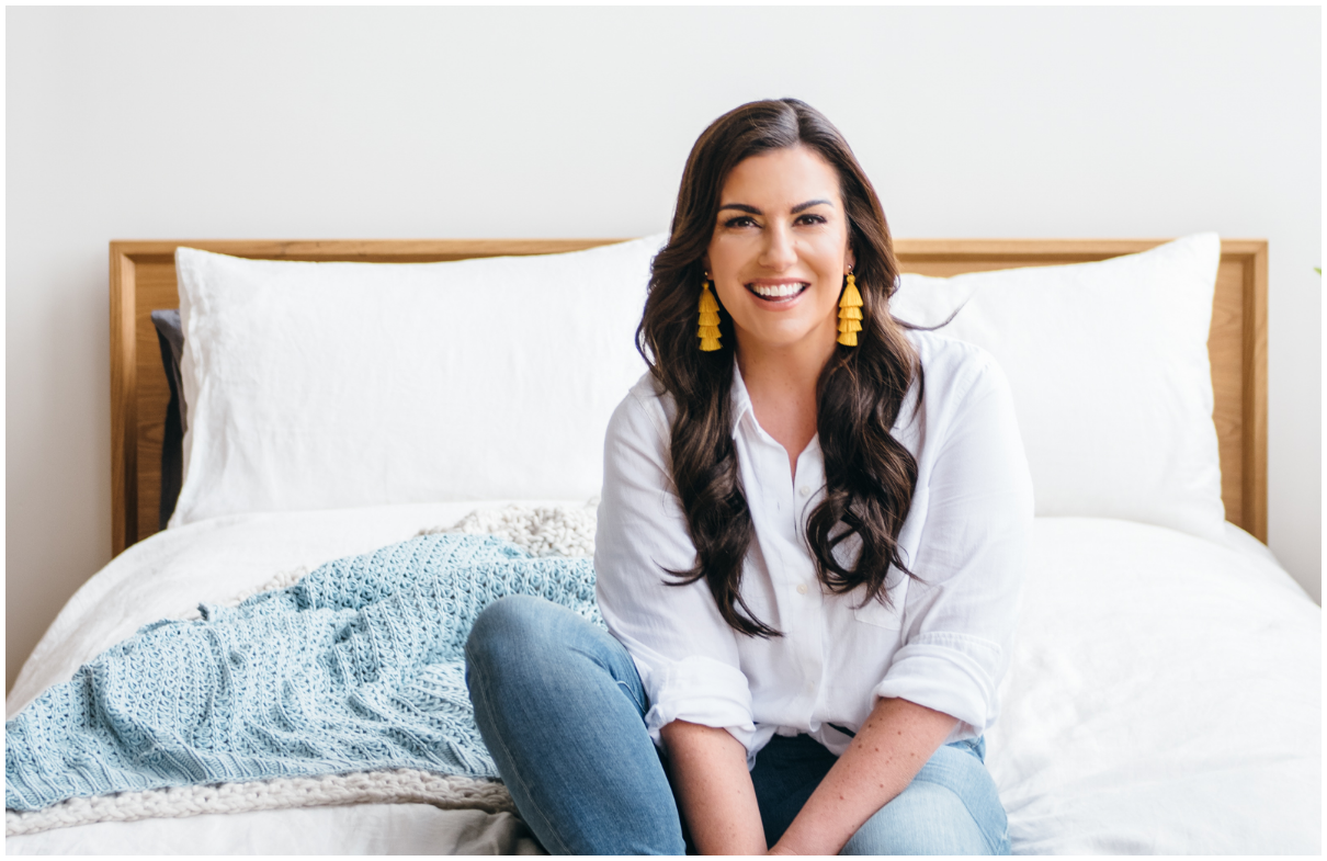 amy porterfield sitting on bed smiling at camera