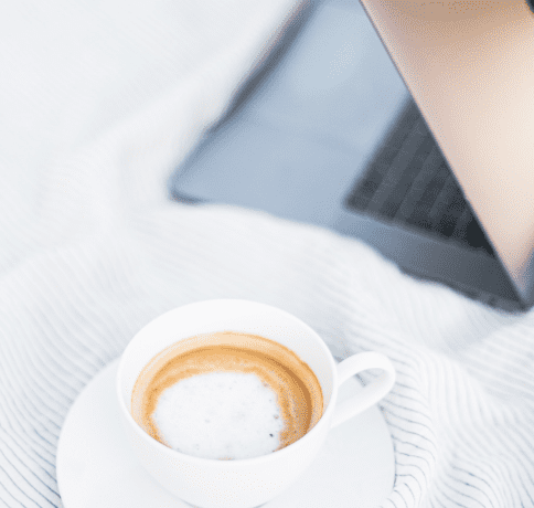 cup of coffee sitting next to laptop