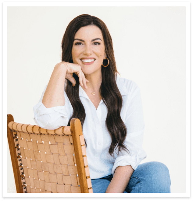 amy porterfield smiling at the camera wearing a white shirt sitting in chair