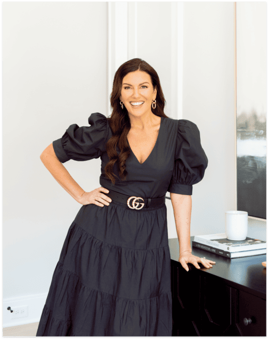 Amy Porterfield wearing a black dress standing in front of a dresser