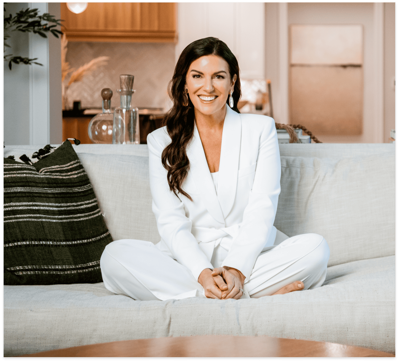 Amy Porterfield wearing white suit sitting on a coach