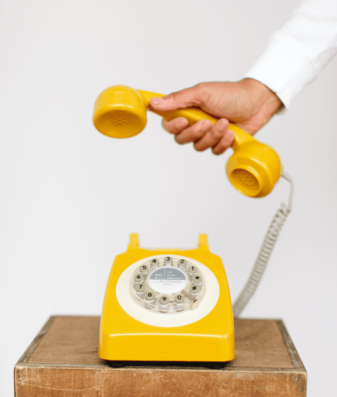 hand holding receiver of yellow rotary phone